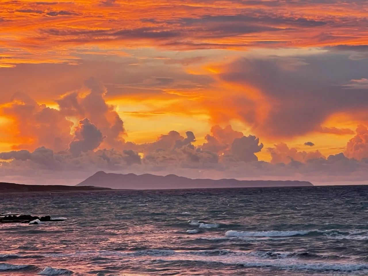 Sea with orange sunset and large clouds